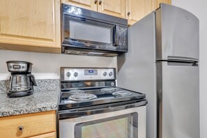 A kitchen with a stainless steel stove, microwave, and refrigerator. - Romantic Condo in City Center- Wright Square Loft C (Savannah)