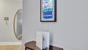 A framed digital display of a building, a mirror, and a small table with a sign. - Romantic Condo in City Center- Wright Square Loft C (Savannah)