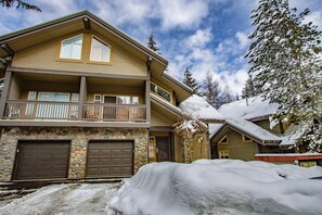 A two-story building with a stone facade, a balcony, and a garage. - Snowy Creek 4 - Ski in Ski out, Private Hot Tub, Short Walk to Whistler Village (Whistler)