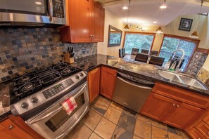 A modern kitchen with a gas stove, oven, dishwasher, and granite countertops.