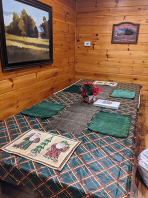 Quarto de cabana de madeira com cama, um letreiro de boas-vindas emoldurado e uma pintura de um celeiro.