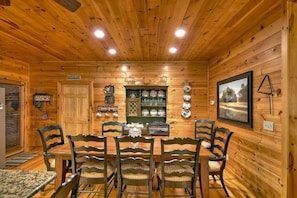 Uma sala de jantar com painéis de madeira, uma mesa central, cadeiras e decorações nas paredes.