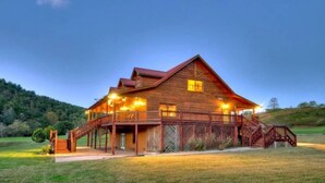 A large wooden cabin with a porch, multiple windows, and a staircase leading to the entrance.