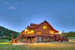 A large wooden cabin with a porch, multiple windows, and a staircase leading to the entrance.