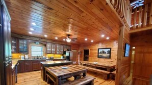 A wooden interior with a kitchen, dining area, and a staircase.