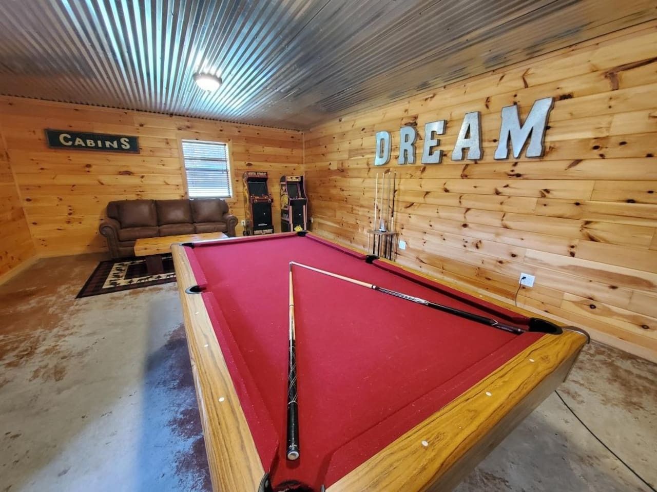 A pool table in a room with wooden walls and a sign that reads 'DREAM.'