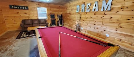 A pool table in a room with wooden walls and a sign that reads 'DREAM.'
