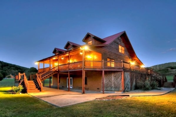 A large wooden building with multiple levels, a balcony, and a staircase leading to the upper floor.