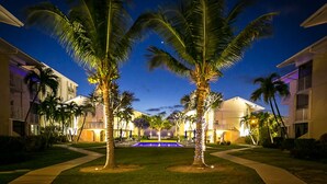Un resort con piscina, palmeras y edificios con balcones.