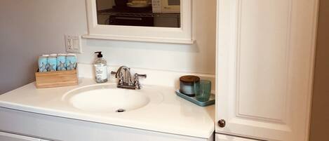 Une salle de bain avec un meuble-lavabo blanc, un double vasque et un miroir au-dessus du lavabo.
