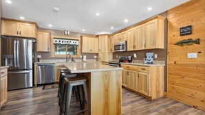 A modern kitchen with wooden cabinets, stainless steel appliances, and a central island with bar stools.