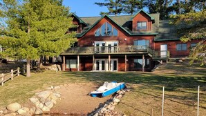 A large wooden cabin with a balcony, a dock, and a small boat.