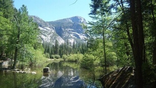 Un lac paisible, entouré d’une forêt dense et de montagnes.