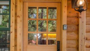 L’entrée d’un chalet en bois, avec une pancarte de bienvenue, une porte en verre et une lanterne.
