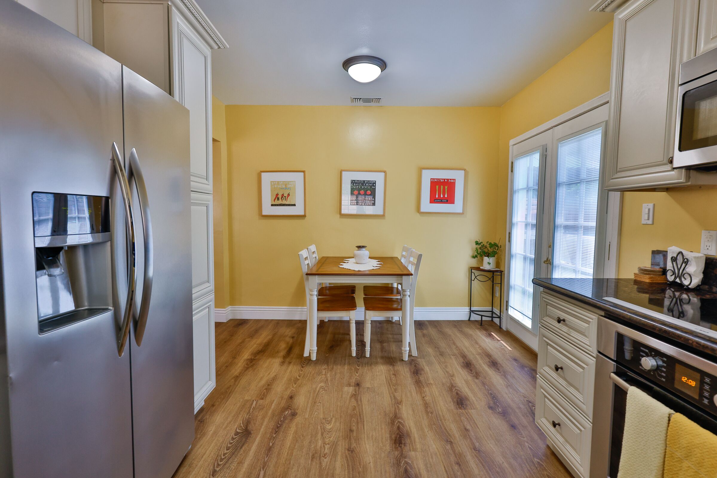 Una cocina equipada con refrigerador, estufa, microondas y una mesa de comedor con sillas.
