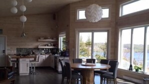 Un grand espace de vie comprenant un canapé, une table à manger avec des chaises et une cuisine à l’arrière-plan.