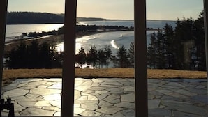 Une pièce dotée d’une grande fenêtre donnant sur un paysage magnifique, comprenant une étendue d’eau et une zone boisée.
