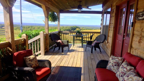 En træterrasse med fletmøbler, en rød sofa og et bord.