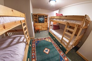 A room with two bunk beds, a wooden dresser, a television, and a patterned rug. - Pinnacle Ridge 38 – Ski in Ski out, Wood Fireplace (Whistler)