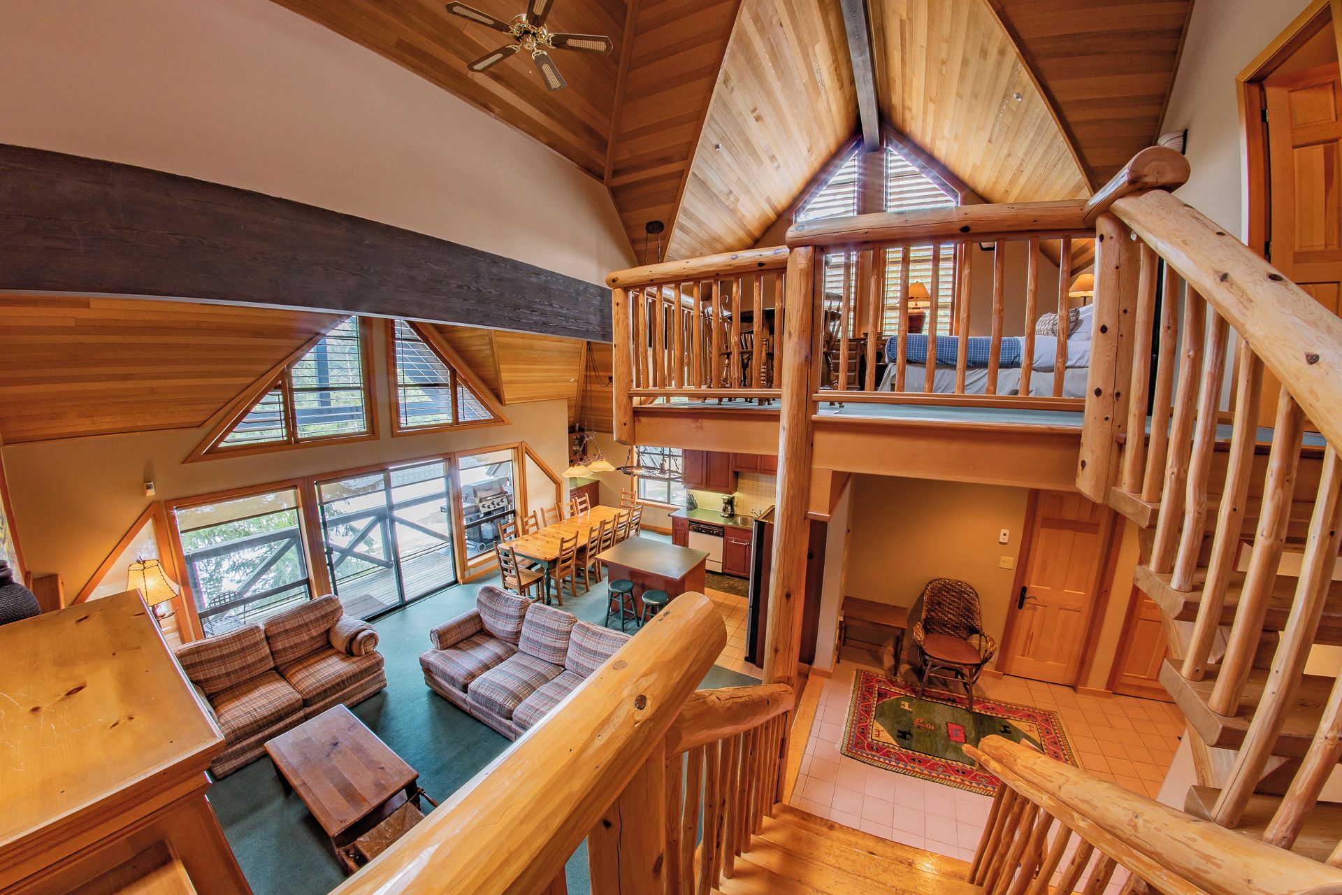 A spacious loft-style room with a high ceiling, wooden beams, and a mezzanine level with a balcony.