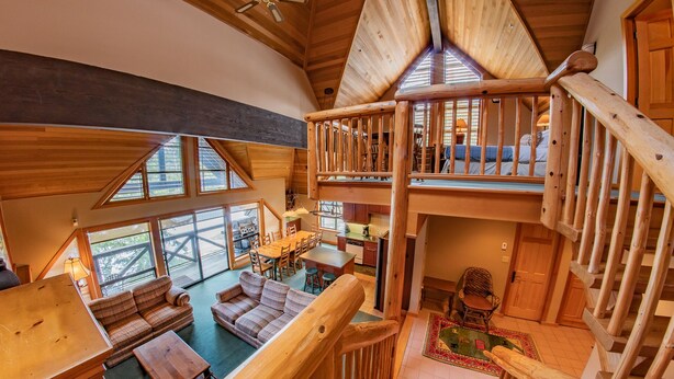 Ruime loft-achtige kamer met een hoge plafond, houten balken en een entresol met balkon.