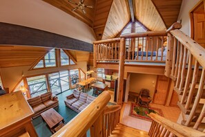 A spacious loft-style room with a high ceiling, wooden beams, and a mezzanine level with a balcony. - Pinnacle Ridge 38 – Ski in Ski out, Wood Fireplace (Whistler)