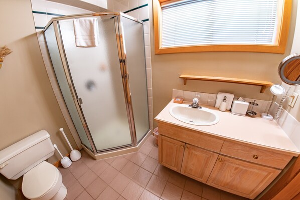 A bathroom with a glass shower enclosure, a toilet, a sink, and a vanity with cabinets. - Pinnacle Ridge 38 – Ski in Ski out, Wood Fireplace (Whistler)