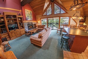A spacious living area with a fireplace, a sofa, a dining table, and a bar area. - Pinnacle Ridge 38 – Ski in Ski out, Wood Fireplace (Whistler)
