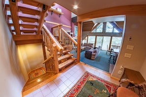 Staircase leads to an upper level, with a seating area featuring a sofa, chairs, and a rug on the tiled floor.