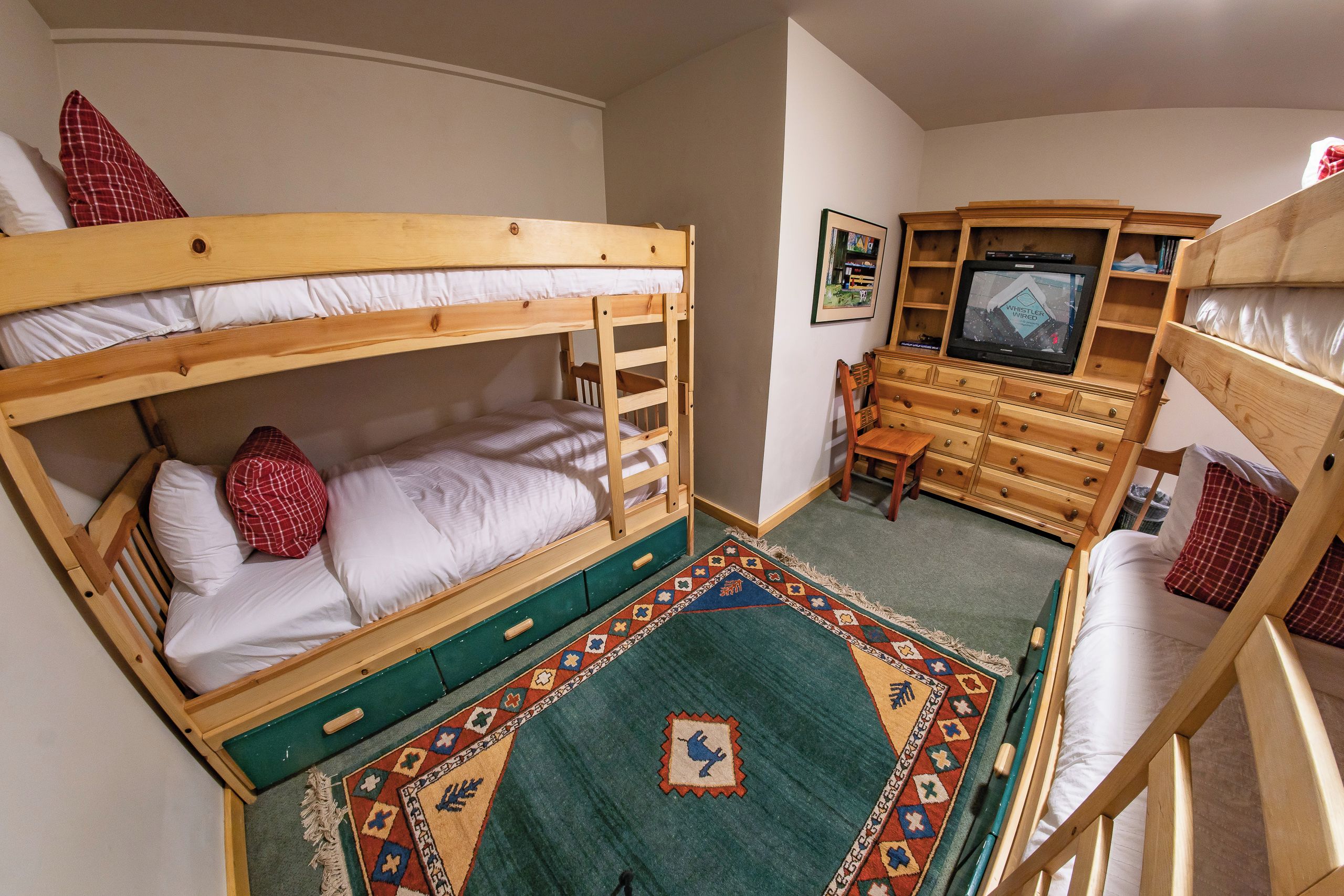 Une chambre avec un lit superposé, une télévision et un bureau.