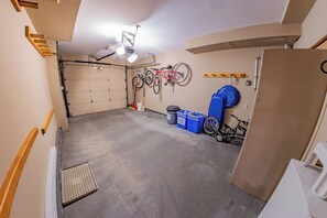 Autotalli, jossa on betonilattia, pyörä on kiinnitetty seinään ja ovi johtaa toiseen huoneeseen.