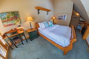 A bedroom with a wooden bed, two bedside tables, a chair, a desk, a shelf, and a painting on the wall. - Pinnacle Ridge 38 – Ski in Ski out, Wood Fireplace (Whistler)