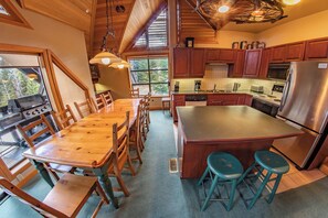 A spacious kitchen with wooden cabinets, a central island, and a dining area with wooden chairs.