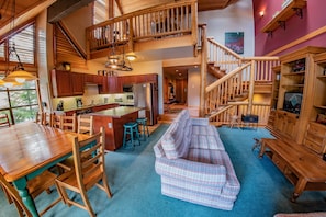 Cozy living space with a dining area, central seating, and kitchen, connected by a staircase.