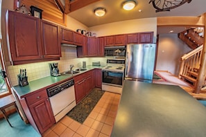 A modern kitchen with wooden cabinets, stainless steel appliances, and a built-in microwave.