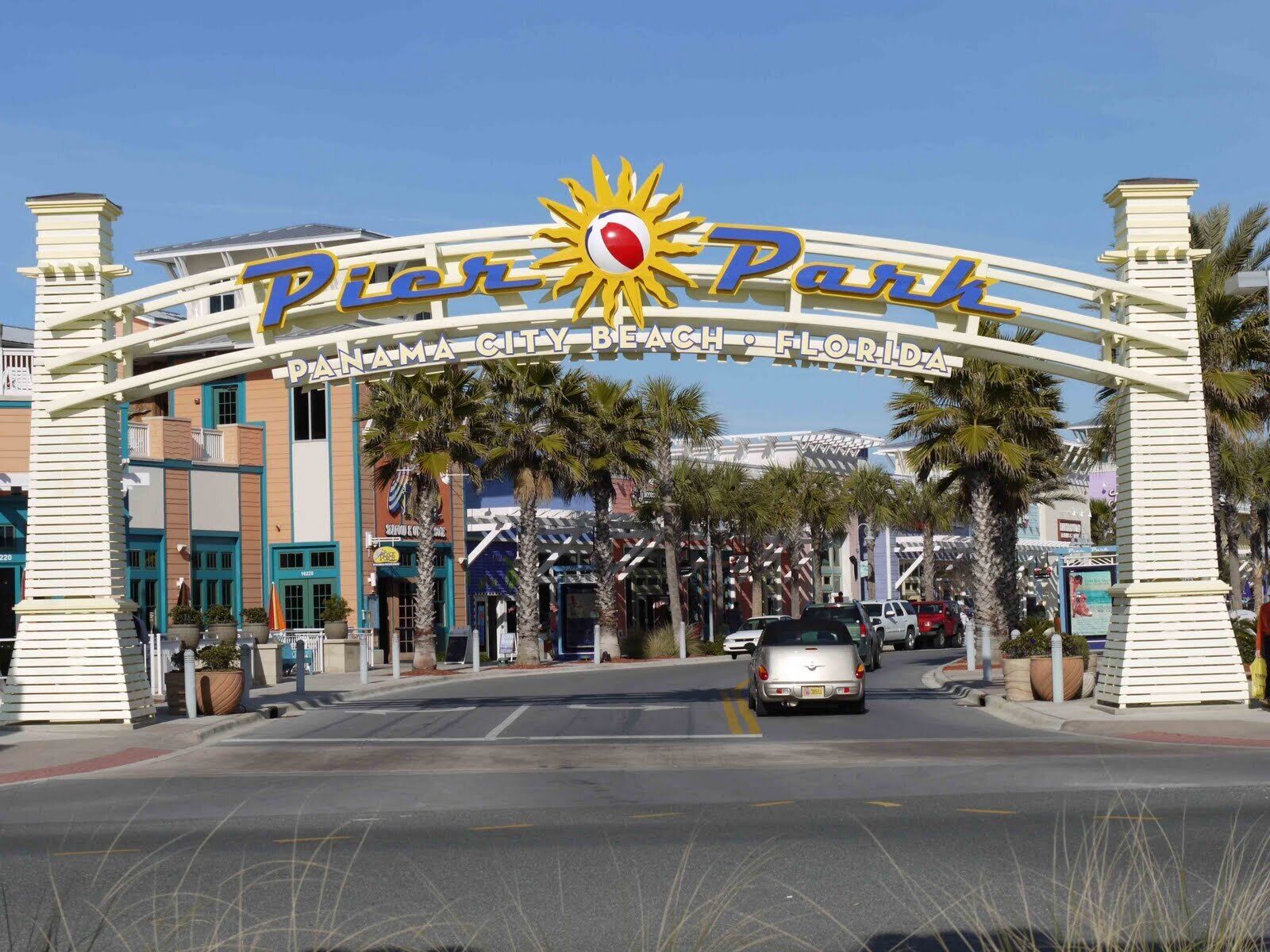A sign for Pier Park in Panama City Beach, Florida, with a sun emblem and palm trees.