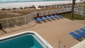 Un espace piscine avec des chaises longues et vue sur la plage.