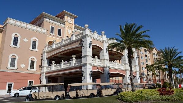 A multi-story hotel with a central atrium, balconies, and palm trees.