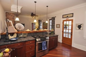 A kitchen with a central island, wooden cabinets, a stove, and pendant lighting.