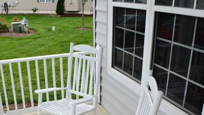 Une véranda avec deux fauteuils à bascule et une balustrade blanche.