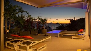 A modern outdoor lounge area with sun loungers, a pool, and a view of the ocean at sunset. - NEW Villa AKA walking distance to the beach (Saint Barthelemy)