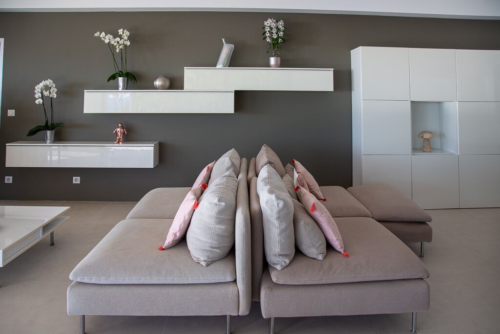 A modern living room with a sofa set, white shelving units, and decorative plants.