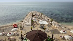 På stranden, solsenger, parasoller og strandbar