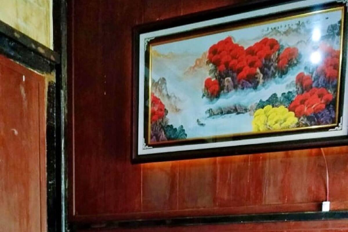 A room with two beds, a wooden wall, and a framed painting above the beds.