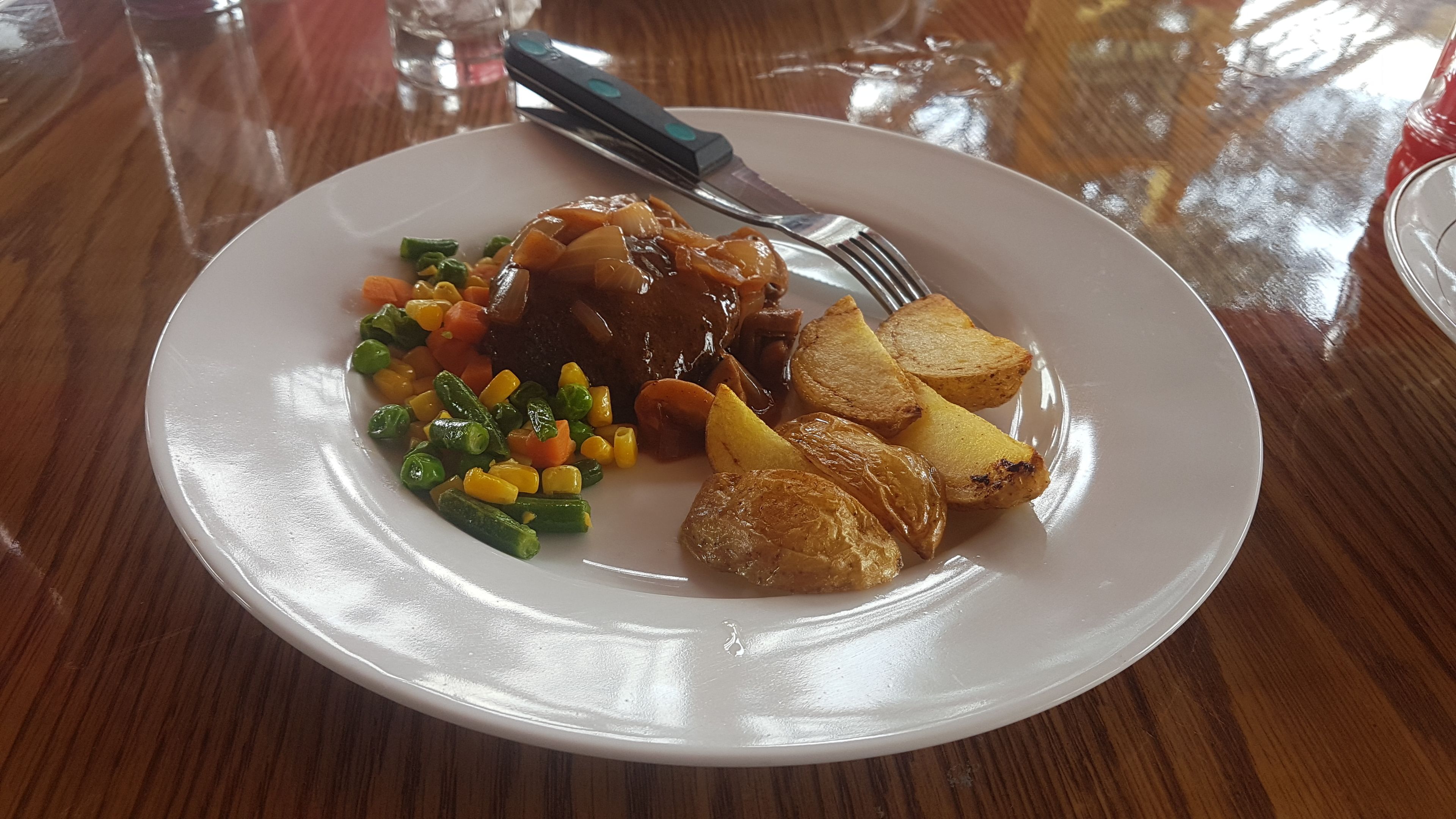 Un plato de comida con un bistec, patatas asadas y verduras mixtas.