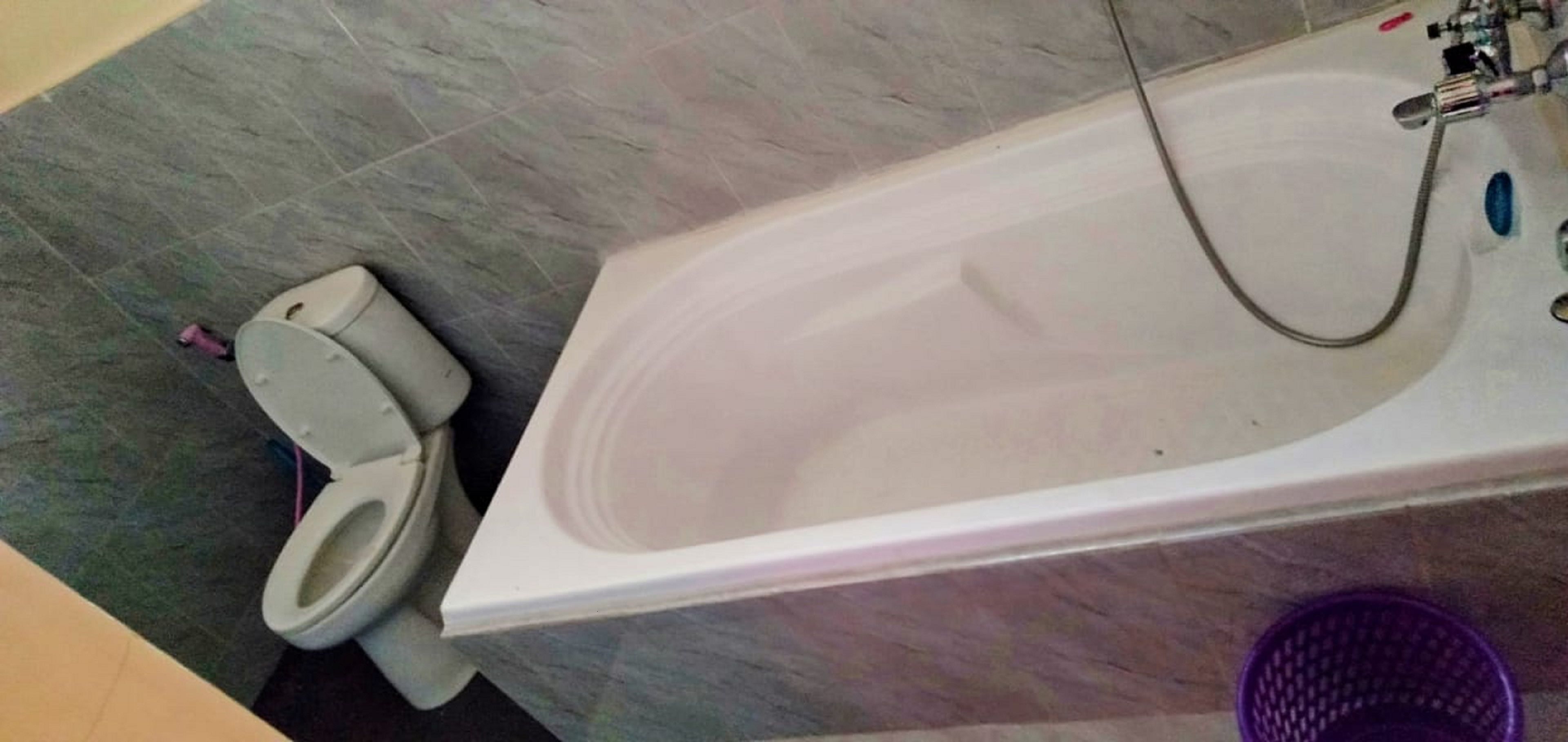 A bathroom with a white bathtub, a toilet, and a purple basket.