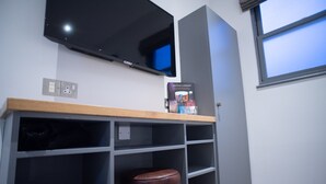 Una habitación con un televisor montado en la pared, una estantería con un libro titulado 'Crafting a Company' y un taburete.