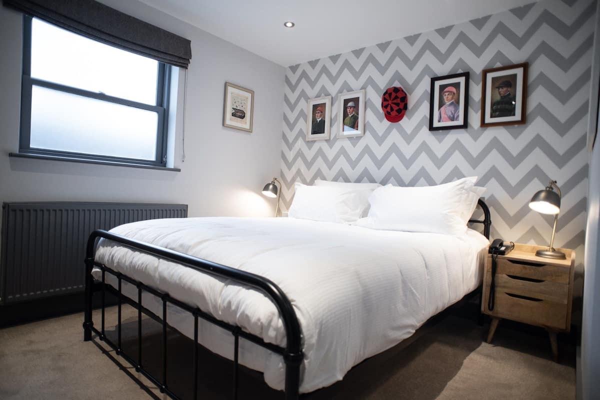 A bedroom with a bed, bedside tables, and a window.