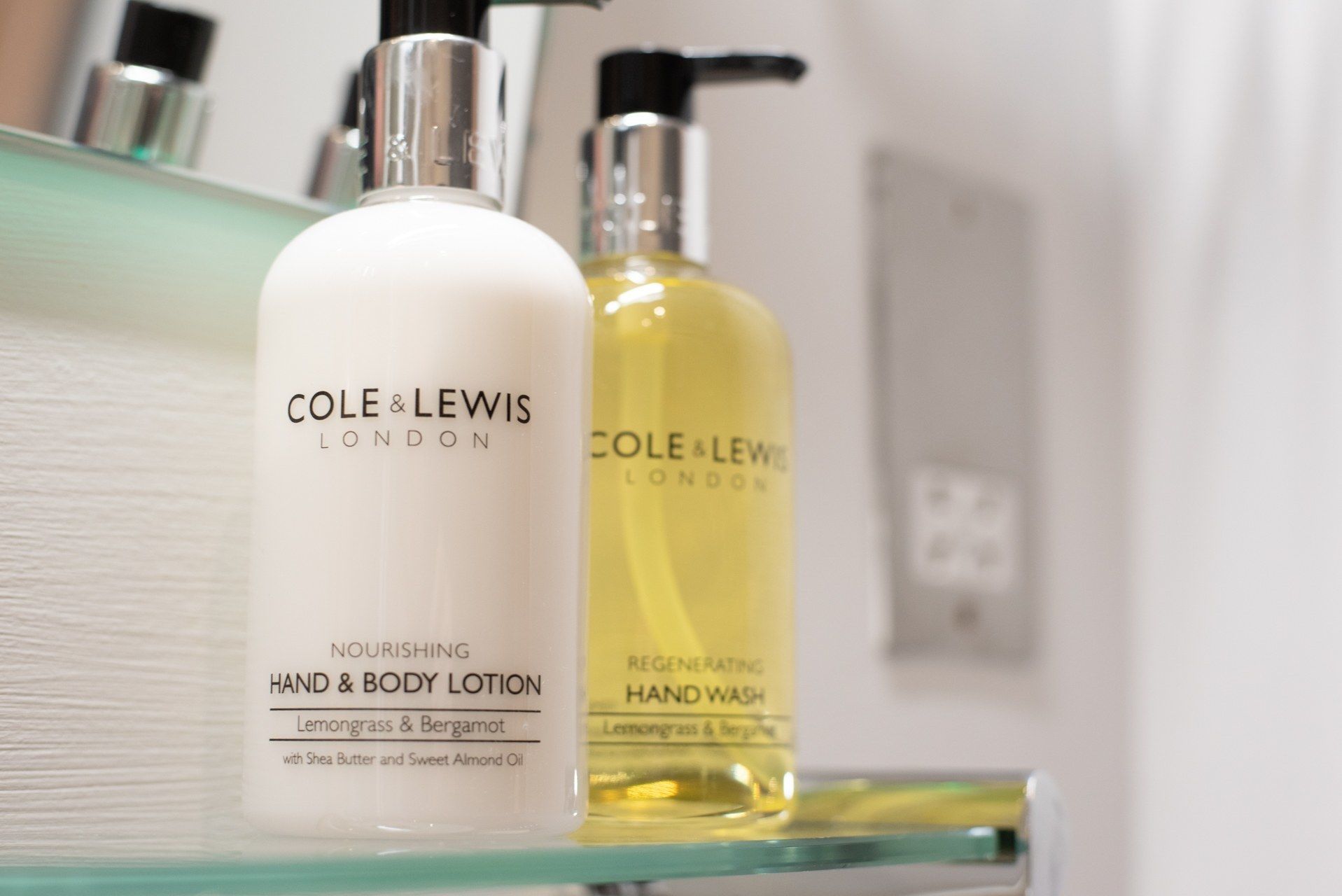 Two bottles of Cole & Lewis London hand and body lotion and hand wash on a bathroom shelf.