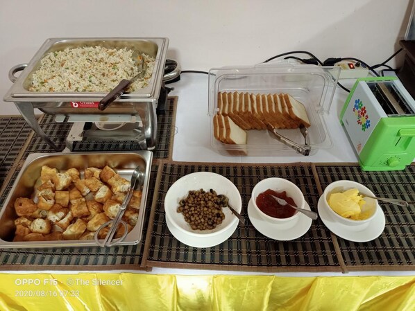 Disposición de buffet con diversos alimentos, incluyendo arroz frito, pan, tofu frito y salsas.